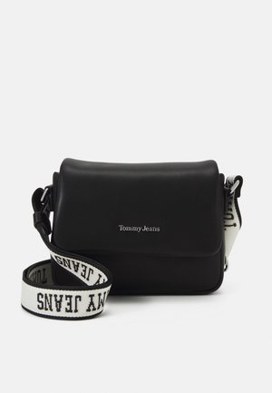 Zwarte Tommy Jeans crossbodytas met klep en verstelbare witte stoffen band met zwarte "Tommy Jeans" tekst.