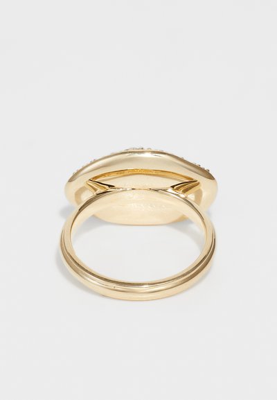 Bague en or avec un dessus arrondi et lisse, présentant un bord légèrement surélevé. L'anneau est mince et poli, avec une texture douce.