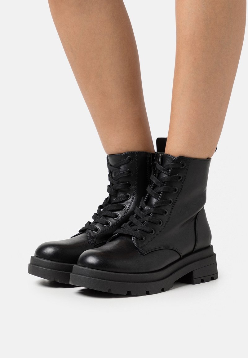 Black leather combat boots with a round toe, lace-up front, high ankle, and textured rubber sole for traction.