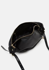 Zwarte leren handtas met ritsluiting, verstelbare schouderriem en een ruime binnenkant met een ritsvak. Soepele textuur en minimale hardware.