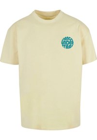 Camiseta de algodón amarillo claro con cuello redondo. En la parte delantera presenta un gráfico circular turquesa con el texto "Baila bajo las estrellas".