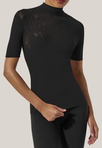 Svart åtsittande topp med korta ärmar, hög halsringning och en genomskinlig blommig mönster på ena axeln, tillverkad av elastiskt material.