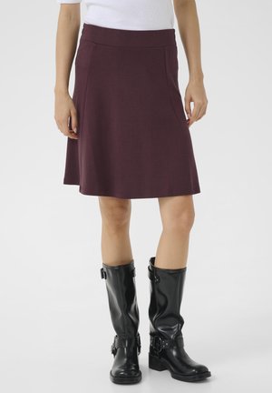 Jupe évasée bourgogne avec une texture lisse, dotée d'une taille ajustée et de coutures latérales discrètes, associée à des bottes en cuir noir montant jusqu'aux genoux.