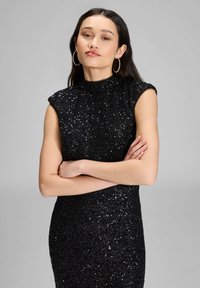 Mustaherkkäiset kimalteet, vartalonmyötäinen mekko, jossa on korkea kaulus ja hihattomat hihat. Mekossa on teksturoitu pinta ja tiukka siluetti.