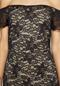 Vestido de renda preta com padrões florais, design à portuguesa e tecido texturizado. Forrado com uma camada interior nude para maior cobertura.