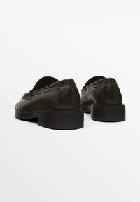 Brown leather loafers with a rounded toe, low block heel, and seam detailing. Smooth texture and subtle shine on a plain background.