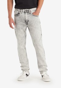 Light gray denim jeans with a faded wash, straight-leg fit, five-pocket design, black stitching accents, worn with white sneakers.