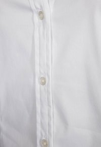 White cotton shirt with a button-down front, featuring six clear buttons, neat stitching, and smooth fabric texture.