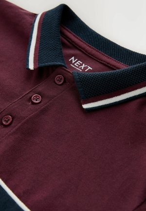 Burgunderfarvet polo med en tekstureret navykrave, tre knapper og hvide-røde striber på kraven. Labelen står "NEXT."