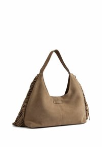 Borsa a tracolla in suede marrone con forma curva, caratterizzata da frange laterali e un’etichetta. La tracolla è robusta ed è progettata per essere portata sulla spalla.