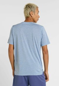 Camisa atlética de manga corta para hombres en azul claro, hecha de una tela que absorbe la humedad con un acabado texturizado, con ventilaciones laterales en el dobladillo.