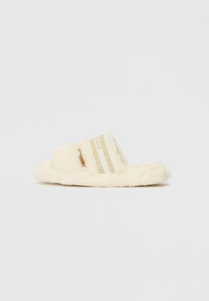 Fuzzy cream-colored slide sandals with two beige striped straps. Soft texture with a flat sole and open-toe design.