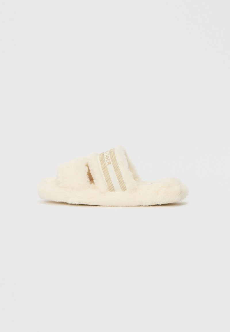 Fuzzy, crèmekleurige slide-sandalen met twee beige gestreepte banden. Zachte textuur met een platte zool en open teenontwerp.