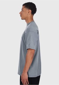 Gray cotton t-shirt with a relaxed fit, round neckline, and short sleeves. Subtle logo detail on the sleeve, smooth texture.
