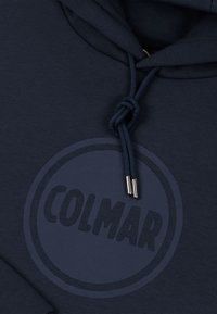 Felpa con cappuccio blu navy in cotone, con un grande logo circolare dello stesso colore e cordoncino di plastica con terminali in metallo per la regolazione.