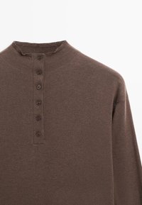 Maglietta henley marrone a maniche lunghe con collo alto, cinque bottoni al colletto e una morbida trama lavorata a maglia.