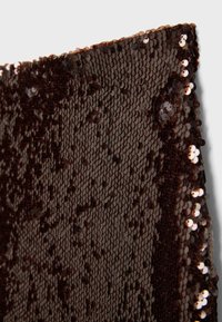 Tissu brun foncé dense recouvert de sequins ronds brillants, montrant une texture détaillée et une surface réfléchissante.