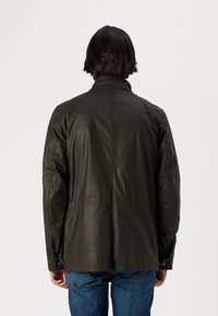 Veste en cuir vert foncé avec un col haut, présentant des empiècements aux épaules et aux coudes, ainsi que des accents de boutons. Montre une vue de dos et un matériau texturé.
