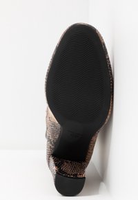 Semelle d'une bottine pour femme avec motif imprimé serpent et une semelle extérieure en caoutchouc noire antidérapante texturée, taille 36 visible.