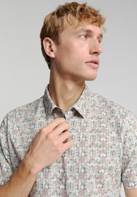 Kurzärmliges Hemd aus leichtem Stoff. Verfügt über ein geometrisches Muster in gedämpften Farben, mit klassischem Kragen und vorderer Knopfleiste.