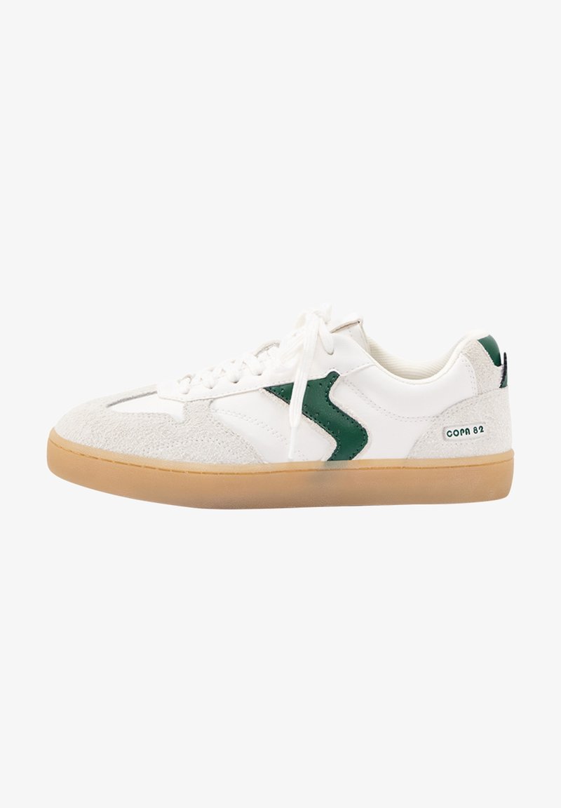 Baskets blanches et beiges avec un détail de logo vert, semelle en gomme, lacets blancs et texte "COPA 82" sur le côté du talon.