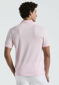 Polo shirt in lichtroze, korte mouwen, met een klassieke kraag. Glad van textuur, subtiele stikdetails en een reguliere pasvorm.