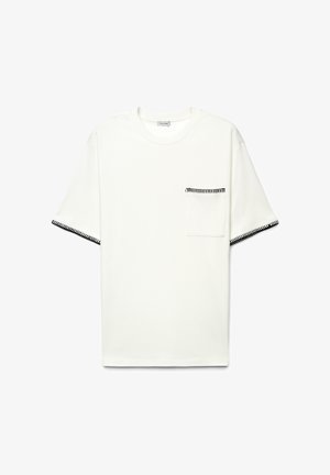 White short-sleeve t-shirt with black zigzag stitching on sleeve edges and a chest pocket, displayed flat on a white background.