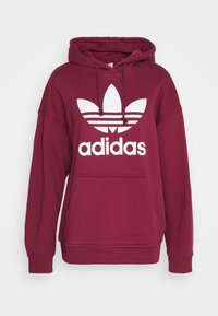 Felpa borgogna con tasca anteriore, cappuccio con coulisse e logo Adidas bianco che presenta il design con tre foglie e tre strisce.