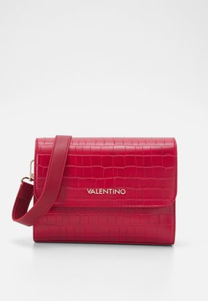 Sac en simili-croc rouge avec une fermeture à rabat, logo doré et une bandoulière réglable pour des options de port polyvalentes.