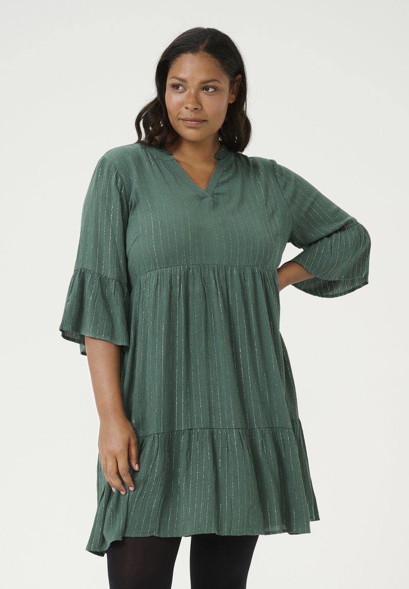 Vestido verde de longitud hasta la rodilla, hecho de una tela texturizada con rayas verticales, escote en V y mangas acampanadas. Detalle de dobladillo de volantes en capas.