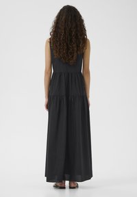 Schwarzes Maxikleid mit ärmellosem Design, schichtweise Konstruktion und leichtem Stoff. Bietet eine entspannte Passform und reicht bis zu den Knöcheln.