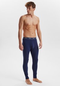 Navy blue thermal leggings with a snug fit, made from soft fabric, featuring a branded elastic waistband and ribbed ankle cuffs.