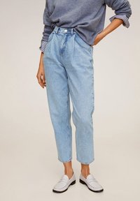 Jasnoniebieskie dżinsy z wysokim stanem o luźnym kroju, zapięcie na guziki, przednie kieszenie oraz lekko zwężane nogawki. Noszone z białymi mokasynami.