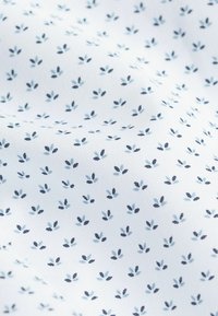 Tejido blanco con un fino patrón de pequeñas hojas azules y marinas, creando una apariencia texturizada. Ideal para prendas ligeras o decoración del hogar.