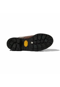 Zapato de cuero marrón con suela de goma negra Vibram. Presenta un patrón de banda de rodadura robusto con acentos azules y una placa de logo metálico.