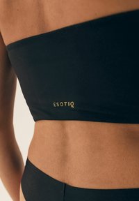 Czarny bikini top bandeau o gładkiej teksturze i dopasowanym kroju, z subtelnym złotym logo "ESOTIQ" na dole.