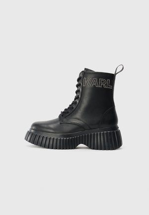 Black leather lace-up boot with chunky ribbed sole and "KARL" studded branding on the side, featuring pull tab at the back.