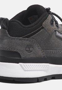 Gray suede and mesh sneaker with black laces, white midsole, and black rubber outsole. Features Timberland logo on the side.
