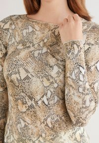 Langarmtop in een slangenprintpatroon met tan, bruin en beige kleuren. Gladde textuur met een ronde halslijn en aangesloten mouwen.