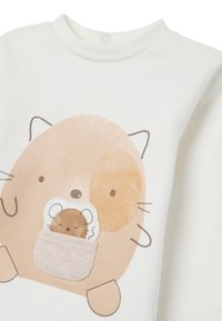 Sudadera de algodón de color crema claro con un diseño de dibujos animados de un gato y un ratón en un bolsillo. Textura suave, cuello redondeado y detalle de botón a presión.