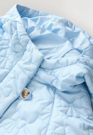 Ljusblå quiltad jacka med hög krage, knappstängning och blommiga sömnadsmönster på mjukt, glansigt tyg.