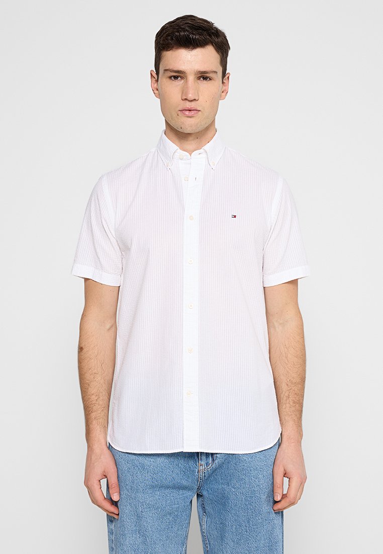 Chemise à manches courtes, à boutons, de couleur blanche avec des rayures verticales subtiles, dotée d'un col classique et d'un petit logo sur la poitrine. En coton.
