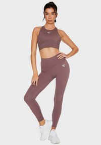 Sportbeha en legging set in mauve, met een soepel, rekbaar materiaal, een hoogsluitend ontwerp en een klein logo op de top en de legging.
