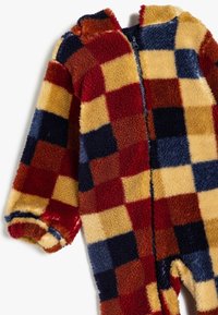 Fleece heldragt med et flerfarvet ternet mønster i rød, gul, marineblå og brun, med lynlås i front og elastiske manchetter.