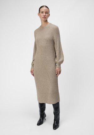 Strikket beige kjole med lange ballongsleeves, ribbestrikket tekstur og rett silhuett. Kombinert med svarte knelange støvler.