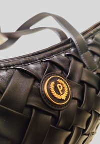 Borsa in pelle tessuta nera con un'emblema rotondo dorato con una "P" e un design di alloro. Texture liscia e cinghie sottili per il trasporto.