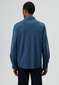 Lange mouwen shirt van donkerblauwe stof, met een kraag en knoopmanchetten. Soepele textuur met een ontspannen pasvorm en een afgeronde zoom.