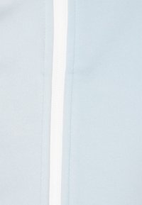 Hellblauer Stoff mit glatter Textur, der einen zentralen weißen Reißverschluss und minimale Nähte für ein sauberes Design aufweist.