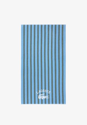 Serviette rectangulaire bleue avec de fines rayures verticales noires et blanches, et logo blanc Lacoste avec un crocodile près d'un coin.