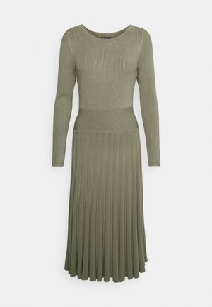 Robe en tricot vert olive à manches longues avec haut côtelé, taille ajustée et jupe plissée sur fond uni.